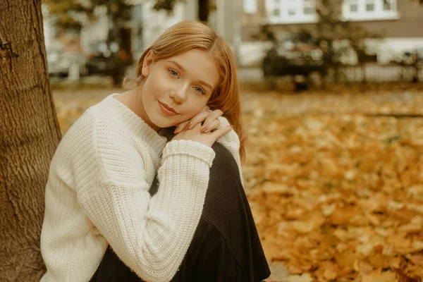 Uma Menina Suéter Branco Senta Nas Folhas Outono Uma Linda — Fotografia de Stock