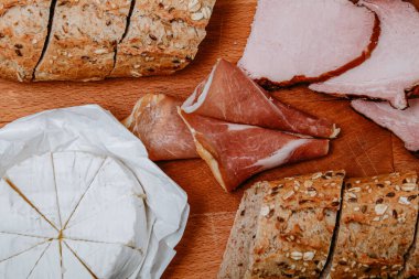 Susam tohumlu baget, peynirli kara ekmek ve tahtada et. Et ve peynirli atıştırmalık, kahvaltı. Güzel yemek fotoğrafı. Atıştırmalık.