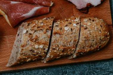 Arka planda bir sürü yemek ve tabak var. Et tabağı ve peynirli peynirli baget. Prosciutto ile salata. Zeytin. Mantarlı ve baharatlı mükemmel sahanda yumurta. Vejetaryen sebze pirzolası ve fıstık. Çatal. Yemek teslimatı.