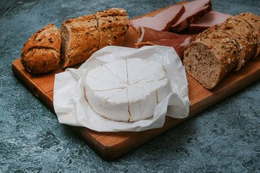 Susam tohumlu baget, peynirli kara ekmek ve tahtada et. Et ve peynirli atıştırmalık, kahvaltı. Güzel yemek fotoğrafı. Atıştırmalık.