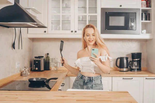 Uma Menina Fones Ouvido Com Telefone Fica Cozinha Prepara Comida — Fotografia de Stock