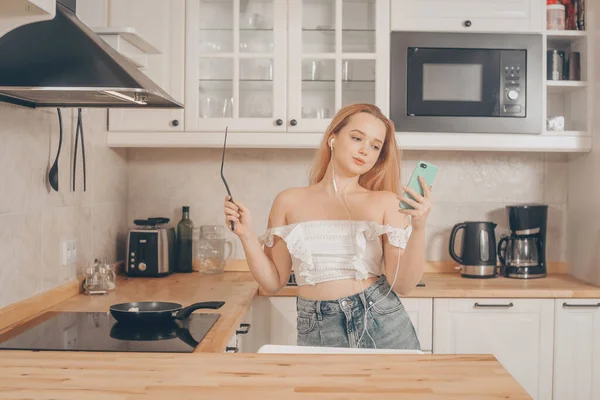 Uma Menina Fones Ouvido Com Telefone Fica Cozinha Prepara Comida — Fotografia de Stock