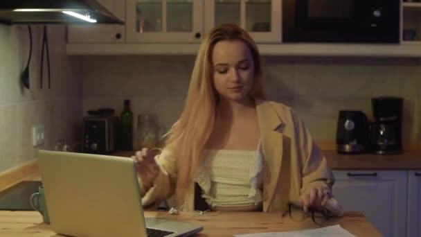 自由职业教师 笔记本电脑后面的女人在家里工作 一个穿着夹克和眼镜的金发美女通过视频通话 老师在网上授课 — 图库视频影像