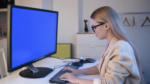 Ein Schönes Mädchen Blickt Einen Großen Monitor Und Druckt Etwas — Stockvideo