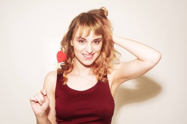 Güzel bir esmer, elinde sopalarla bir kalp tutuyor. Kadınlar günü, 8 Mart, tatil. Beyaz arka planda mutlu bir kız gülümsüyor.