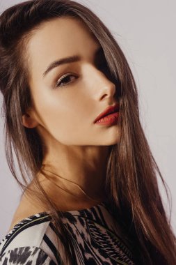 Güzel bir kızın portresi, zarif yüz hatları olan esmer kameraya bakıyor. Uzun, şeytani saçlar