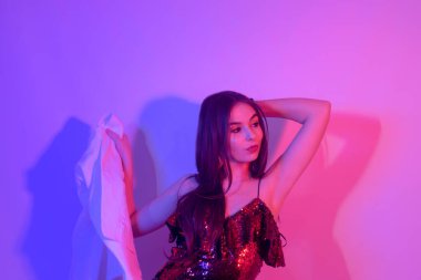 Kırmızı-mavi arka planda neonlu bir kız dans ediyor. Havalı saç kesimi, dans eden gözlüklü, poz veren hippi kız. Kulüpte kürklü bir manken..