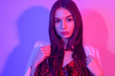 Büyük dudakları, mükemmel kaşları, büyük küpeleri ve pirzolaları olan muhteşem bir esmerin portresi. Her gece dans eden, neon ışıkta şarkılarla dans eden şık bir kız. Bir parti. Beyaz ceketli kız..