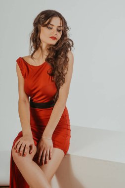 Şehvetli, güzel, esmer kadın seksi kırmızı gece elbisesi içinde poz veriyor. Uzun kıvırcık saçlı, kırmızı arka planda büyük kırmızı dudaklı bir kız. Metinlerimiz için yer, satış, zengin,