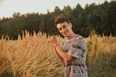 Ormanda buğday tarlasının arka planında yürüyen bir adamın muhteşem bir fotoğrafı. Günbatımının arka planında bir adam, ormanda bir adam, doğa