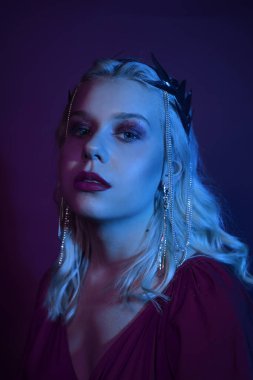 Zincirli gümüş bir taç giymiş neon bir kadın portresi. Prenses, kraliçe, prenses gibi bir kız. Moda, kırmızı ve mavi neonlu bir portre çekiyor. Model çok güzel..