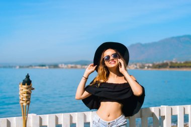 Güzel bir kız telefonda konuşuyor. Sahilin, okyanusun ve denizin zemininde. Büyük siyah şapkalı ve gözlüklü bir kadın tatilde. Serbest çalışan arar, gülümser, gezer ve sohbet eder. Seyahat