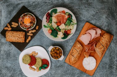 Et, ekmek ve aperatiflerle dolu bir şölen masası. Çırpılmış yumurta, jambon, zeytin ve vejetaryen pirzolası. Öğle yemeği mi akşam yemeği mi? Harika bir kahvaltı. Salata ve peynir..