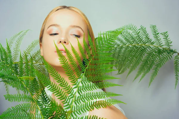 美丽的金发女子有着完美的皮肤和自然的妆容 构成了植物热带绿叶的背景 青少年模特儿的面部护理 — 图库照片