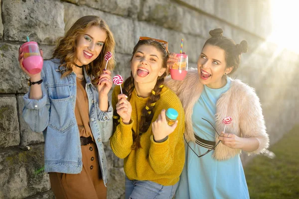 Drei Schöne Mädchen Essen Lutscher Und Trinken Limonade Rosafarbenen Flaschen — Stockfoto
