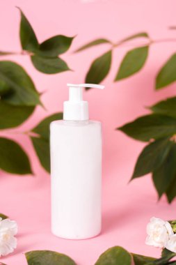 Kozmetik, krem ve şeker, pembe arka planda losyon. Yaprak ve çiçeklerden oluşan beyaz bir şişe. Doğal Kozmetik