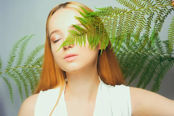美丽的金发女子有着完美的皮肤和自然的妆容 构成了植物热带绿叶的背景 青少年模特儿的面部护理 — 图库照片