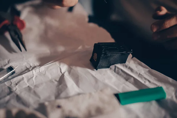 Male hands refill printer cartridge. The guy makes holes in the cartridge and pours ink through the syringe The needle makes a hole in the cartridge