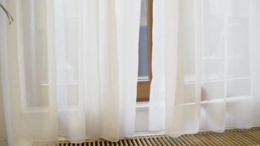 Rüzgarda uçuşan beyaz bir perde. Havalandırma ve balkonun yanında yer ısıtması. Zeminde yalıtım.