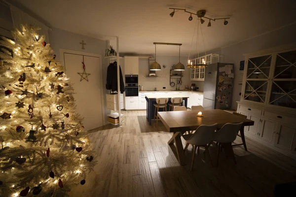 nordic, scandi living room with christmas tree, and warm, cozy atmosphere. White furniture and kitchen in halflight. Style and home interiors idea.