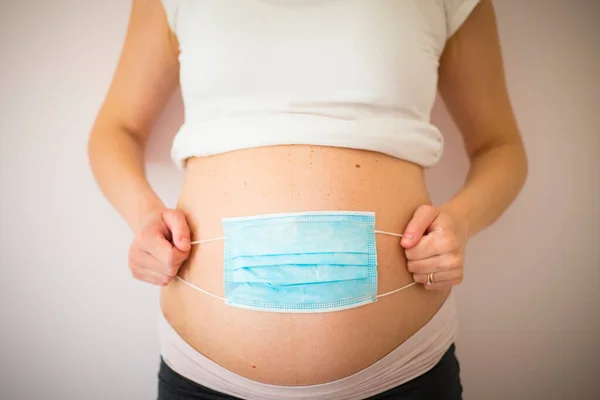 Femme Enceinte Portant Masque Bleu Sur Ventre Pendant Pandémie Covid Photo De Stock