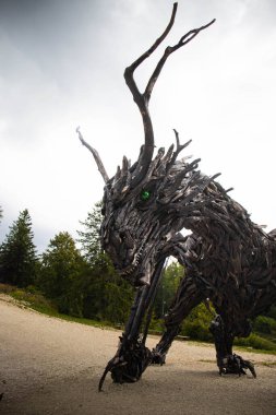 Dünyanın en büyük tahta ejderha heykeli Drago Vaia 'nın muhteşem yüzü, Marco Martalar tarafından kara fırtınalı bir günde kara fırtınalı bir gökyüzü, yan manzara, portre. Lavarone, Trentino, İtalya. Dikey çekim.