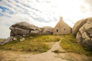 17. yüzyılın ünlü muhafız kulübesi, Fransa 'nın Brittany, Meneham kentindeki eski balıkçı köyünde bulunan iki granit kayanın arasına sıkışmış. Bulutlu yan görüş, insan yok..