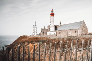 St. Matthew Point 'teki deniz feneri, kilise ve manastır harabeleri Finistere, Brittany, Fransa' da Plougonvelin komününde yer alan bir burundur. Bulutlarla ön manzara, insan yok, dikey çekim.