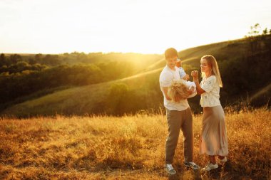 Sahada anaokulu çocuğu olan mutlu ebeveynler, güçlü baba neşeli oğlu baş aşağı tutuyor, sevimli anne gülümsüyor, sevimli aile eğleniyor, birlikte zaman geçiriyorlar, çocukluk konsepti.