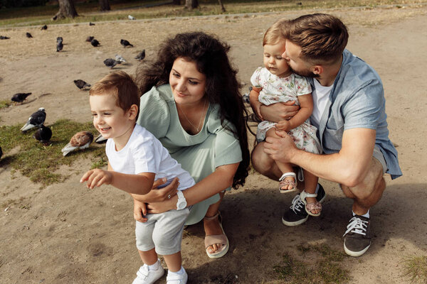 Happy young family with children watching  birds   in the park