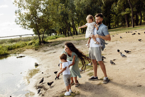 Happy young family with children watching  birds   in the park