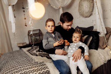 Çocuklu mutlu bir adam yatakta oturuyor. 