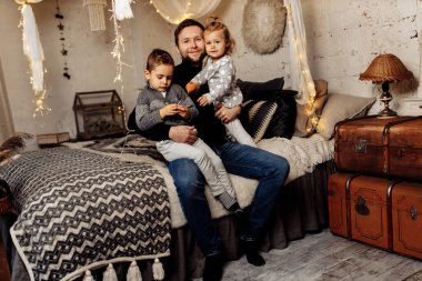 Çocuklu mutlu bir adam yatakta oturuyor. 