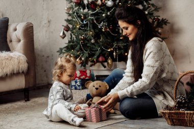 Mutlu anne ve kız yere oturmuş Noel hediyesiyle