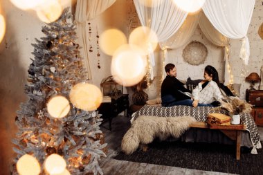 Mutlu çift Noel dekoru ile odada dinleniyor.