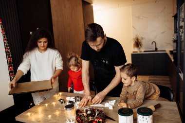 Çocuklu bir aile Noel kurabiyesi pişiriyor.