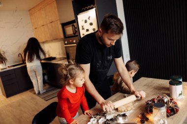 Genç mutlu aile evde Noel gecesi yemek pişiriyor.