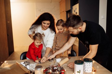 Çocuklu bir aile Noel kurabiyesi pişiriyor.
