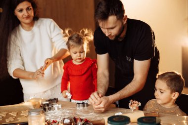 Mutlu aile kurabiyeleri evde mutfakta pişiriyor.