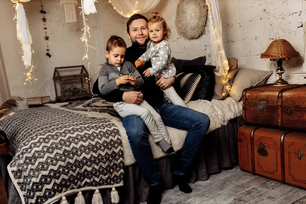 Çocuklu mutlu bir adam yatakta oturuyor. 