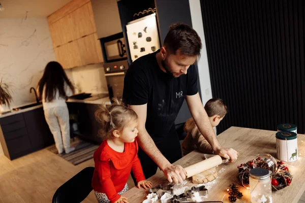 Genç mutlu aile evde Noel gecesi yemek pişiriyor.