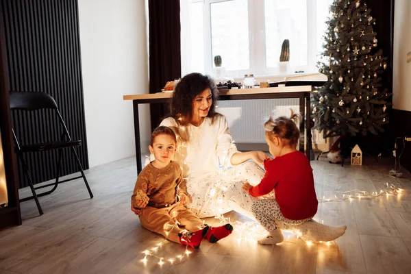 Ευτυχισμένη Οικογένεια Κάθεται Στο Πάτωμα Χριστουγεννιάτικη Γιρλάντα — Φωτογραφία Αρχείου