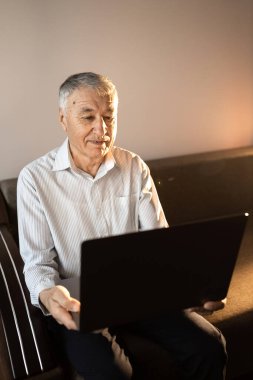 Evde dizüstü bilgisayar kullanan kıdemli adam. 