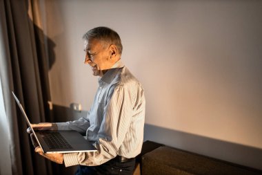 Evde dizüstü bilgisayar kullanan kıdemli adam. 