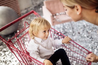 Mutlu genç anne ve oğlu alışveriş arabasında eğleniyorlar. 