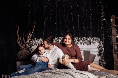 Mutlu genç aile Noel süsleriyle evde poz veriyor.