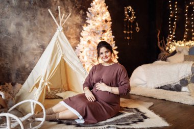 Mutlu güzel hamile kadın evde poz veriyor.