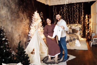 Mutlu evli çift bebek kıyafetleriyle poz veriyor. 