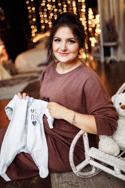 Bebek giysileri tutan hamile kadın 