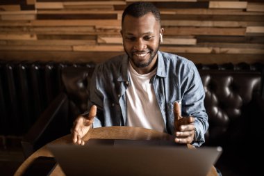 Yakışıklı genç adam masada oturuyor ve dizüstü bilgisayar kullanıyor. 